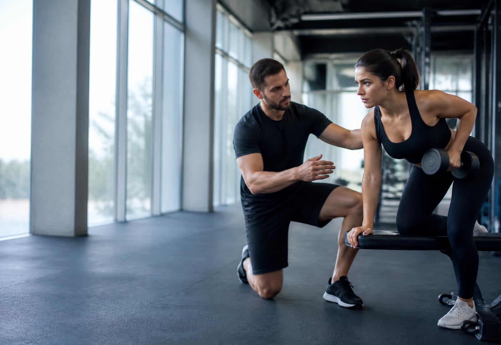 Coach sportif accompagnant une athlète en salle de sport